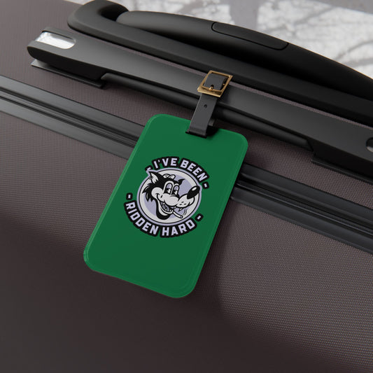 Luggage tag featuring a vintage-style wolf graphic with the phrase "I've Been Ridden Hard", attached to a suitcase.