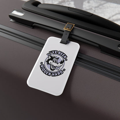 Luggage tag featuring a vintage-style wolf graphic with the phrase "I've Been Ridden Hard", attached to a suitcase.