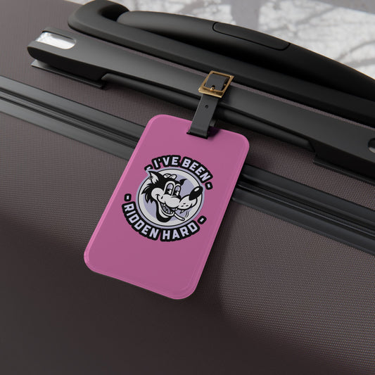 Luggage tag featuring a vintage-style wolf graphic with the phrase "I've Been Ridden Hard", attached to a suitcase.