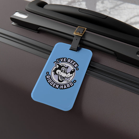 Luggage tag featuring a vintage-style wolf graphic with the phrase "I've Been Ridden Hard", attached to a suitcase.