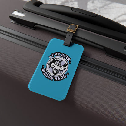 Luggage tag featuring a vintage-style wolf graphic with the phrase "I've Been Ridden Hard", attached to a suitcase.